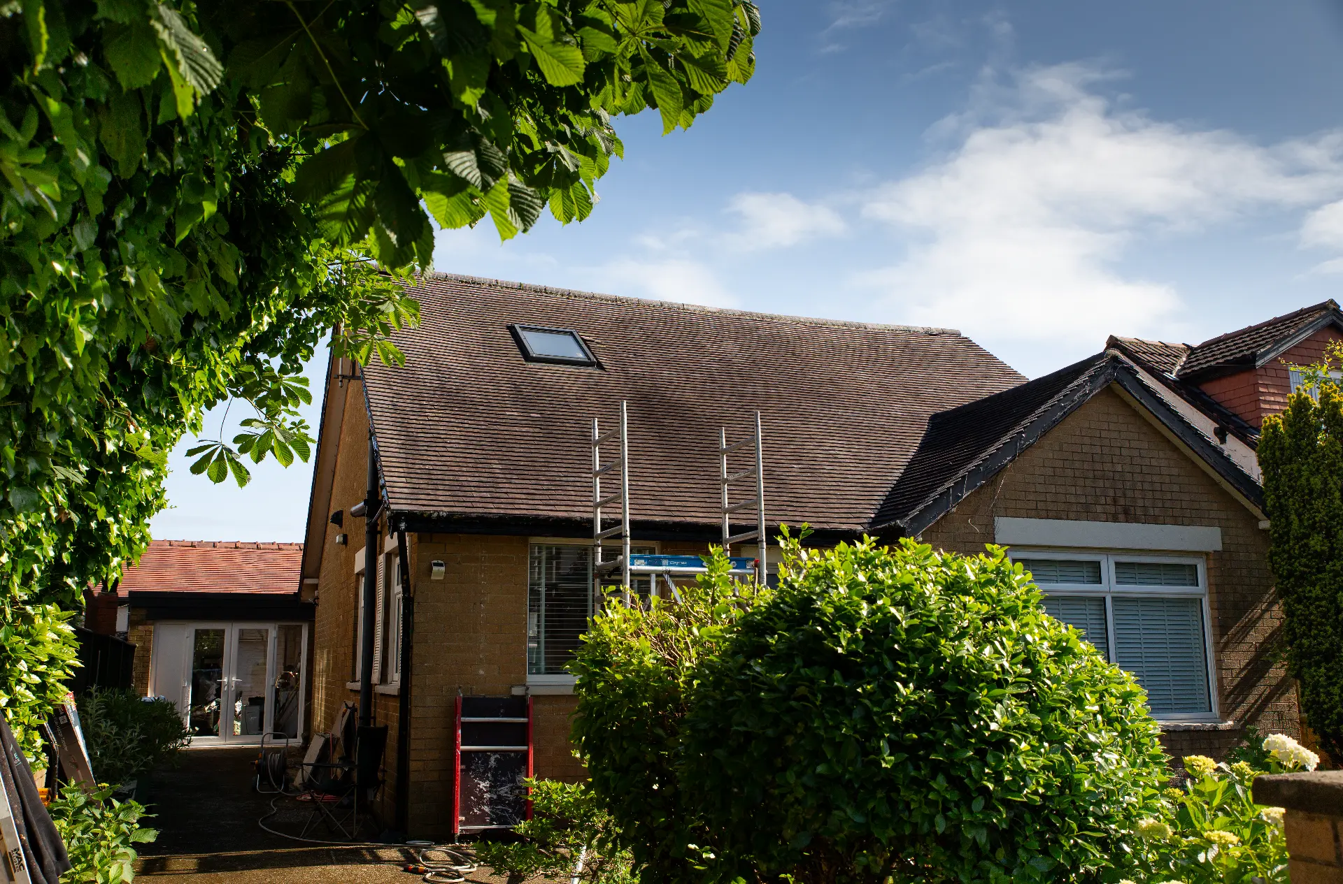 Ladders set up against a tiled roof before cleaning work begins